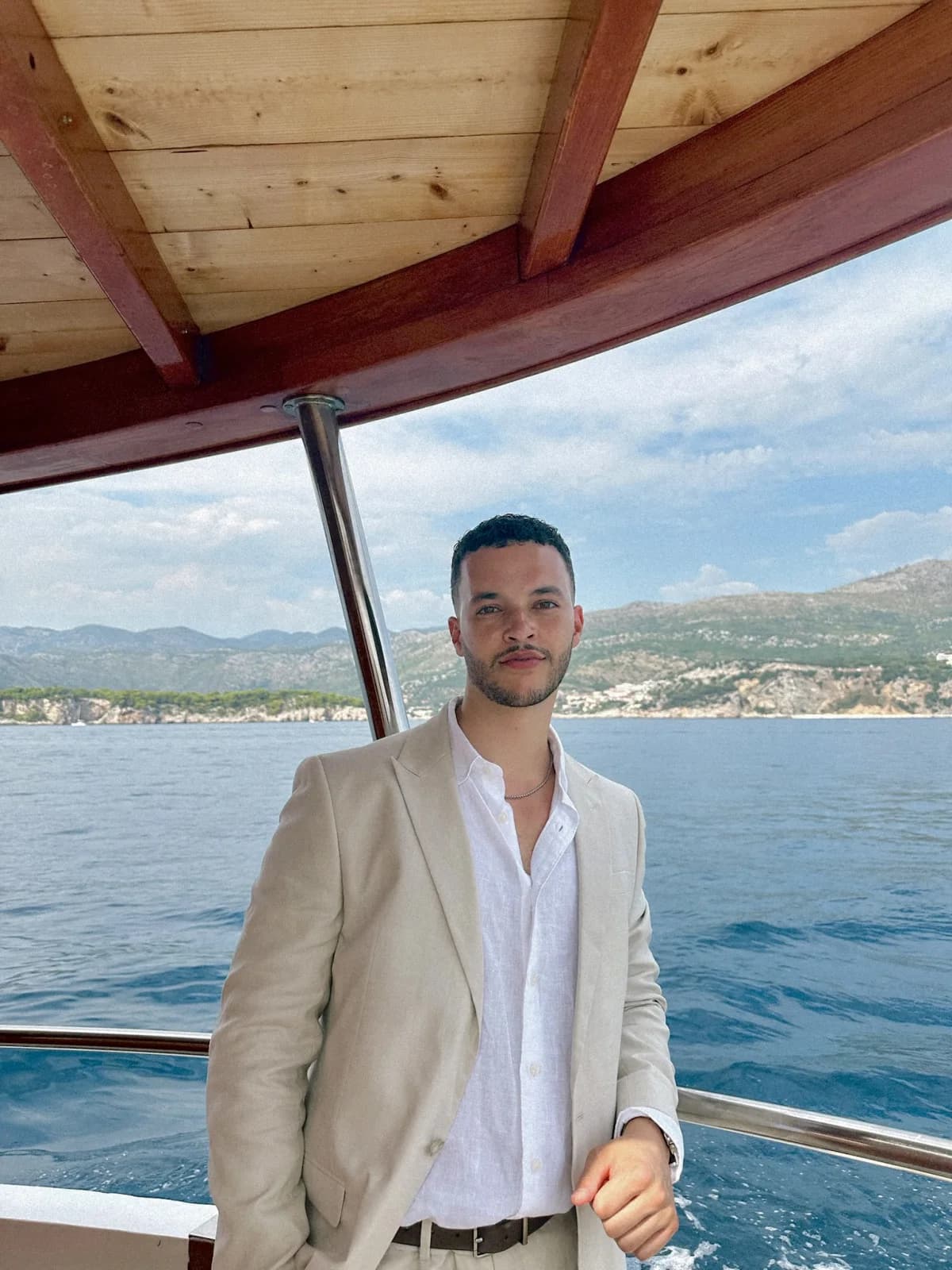 Elias Bennett standing on a boat with the coastline behind him
