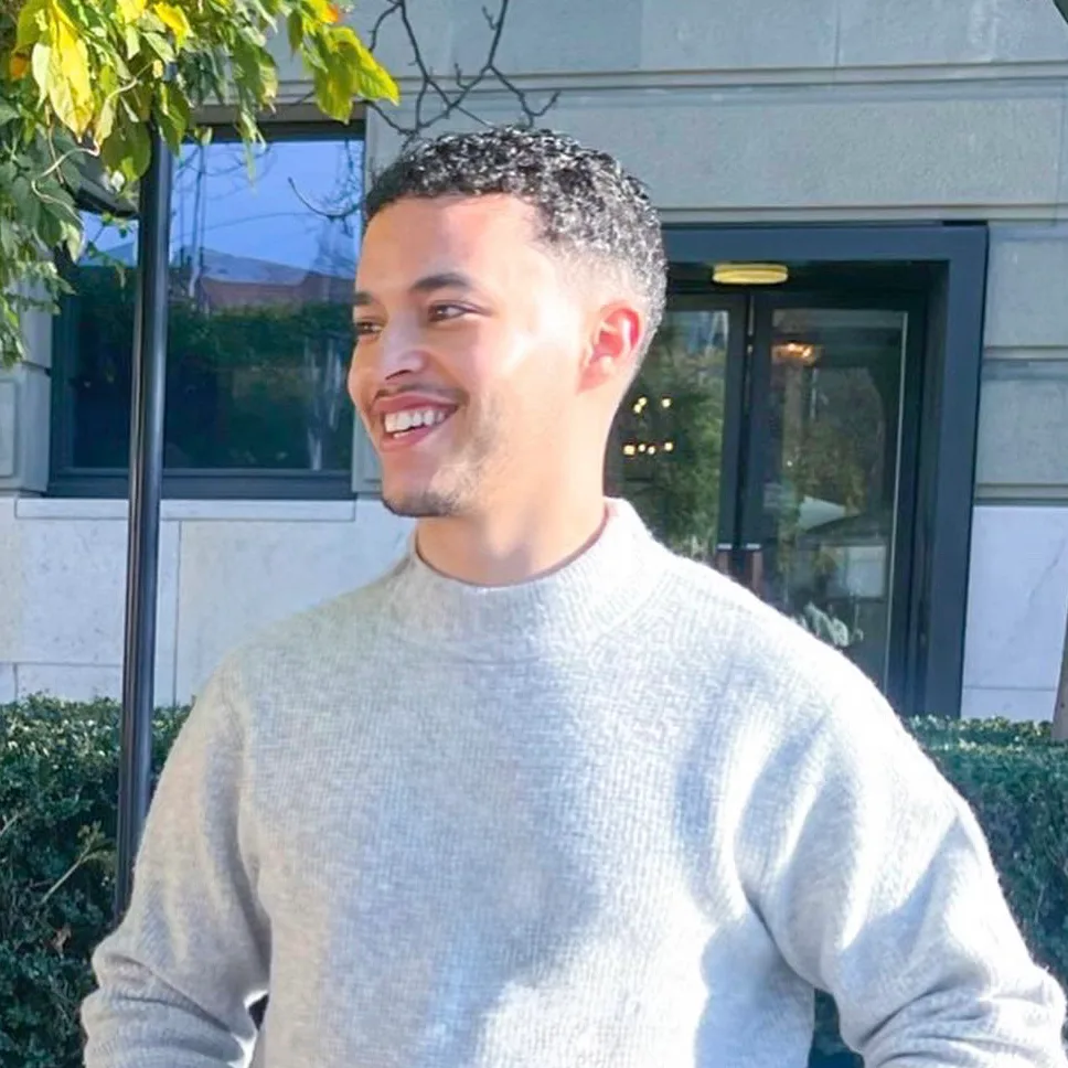 Elias smiling outside in a grey jumper